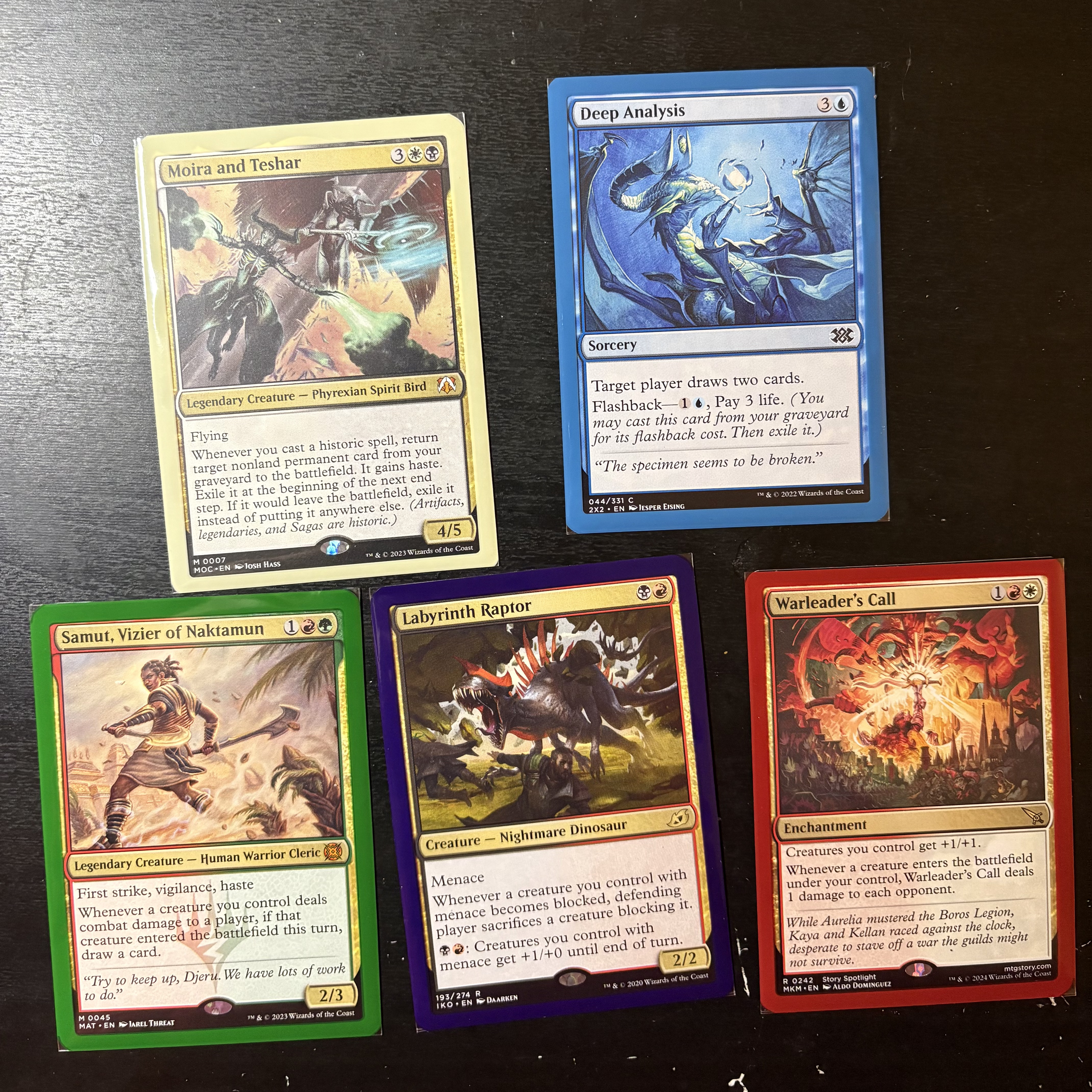 5 magic cards laid out on a table with unusual borders: Moira and Teshar with a cream white border; Deep Analysis with a blue border; Samut, Vizier of Naktamun with a green border; Labyrinth Raptor with a dark purple border; and Warleader's Call with a red border.